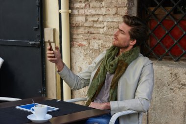 Açık bir kafede smartphone ile genç adam