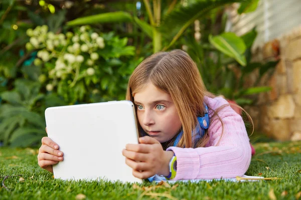 Blondes Mädchen mit Tablet-PC auf Rasen liegend — Stockfoto