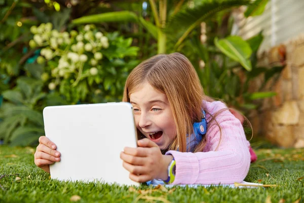 Blond liten flicka med TabletPC liggande på gräs turf — Stockfoto