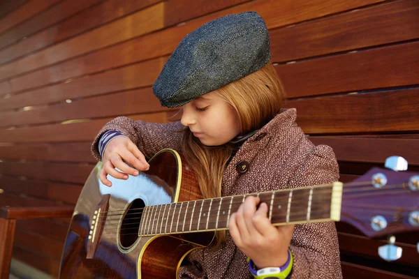 Blond liten flicka spela gitarr med vintern basker — Stockfoto