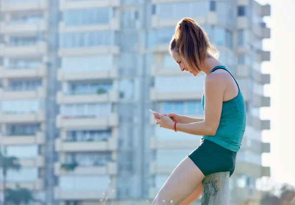 Бегущая девочка отдыхает и пользуется смартфоном на улице — стоковое фото