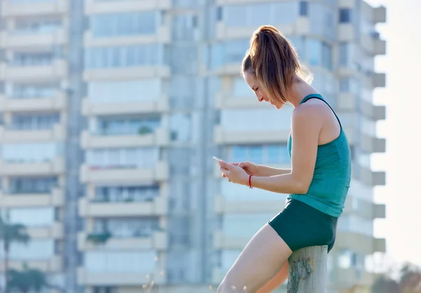 Runner ragazza avendo un riposo e utilizzando smartphone telefono all'aperto — Foto Stock