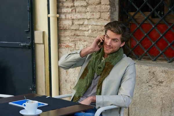 Hombre joven con teléfono inteligente en un café al aire libre — Foto de Stock