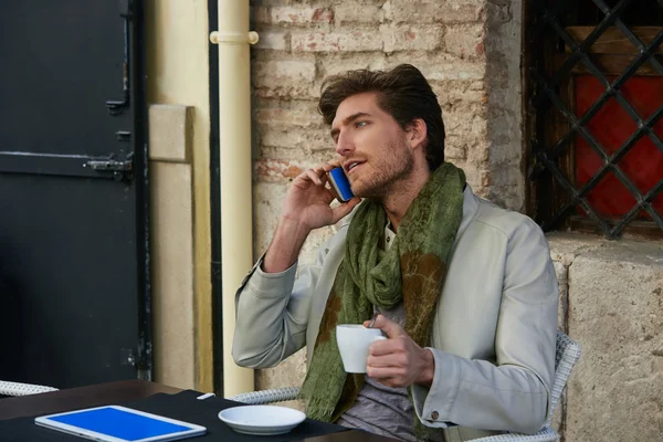 Hombre joven con teléfono inteligente en un café al aire libre — Foto de Stock