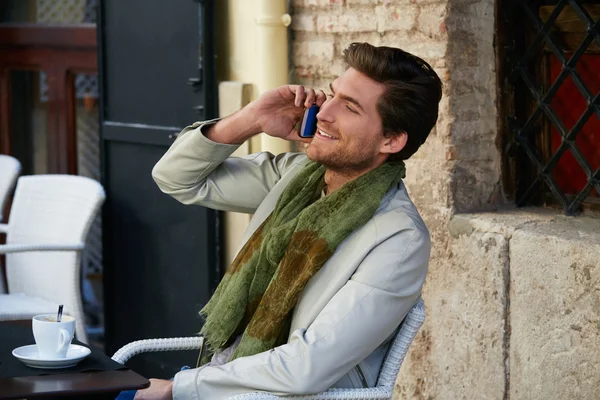 Hombre joven con teléfono inteligente en un café al aire libre —  Fotos de Stock