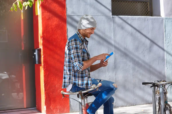 Молодой человек, используя планшетный ПК прикосновение в велосипеде — стоковое фото