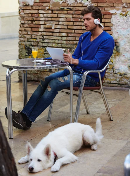 Молодой человек с планшетным ПК прикоснуться к собаке — стоковое фото