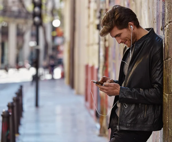 Hombre joven escuchando música teléfonos inteligentes auriculares — Foto de Stock