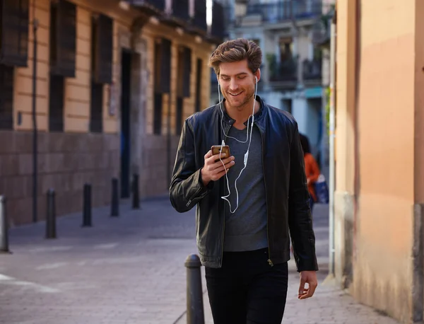 Hombre joven escuchando música teléfonos inteligentes auriculares —  Fotos de Stock