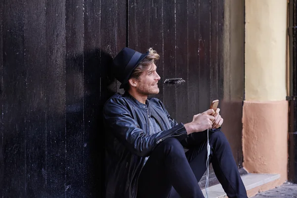 Joven teléfono inteligente hombre sentado calle —  Fotos de Stock
