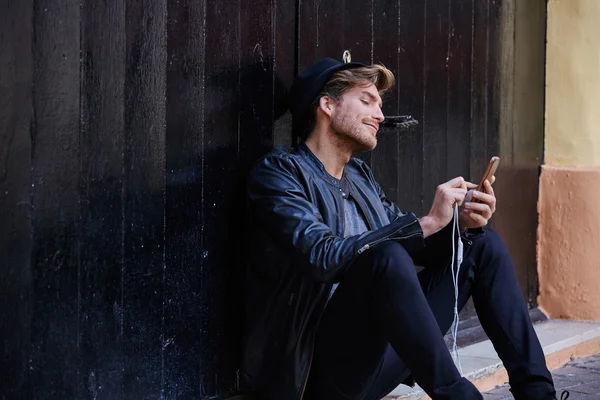 Joven teléfono inteligente hombre sentado calle — Foto de Stock