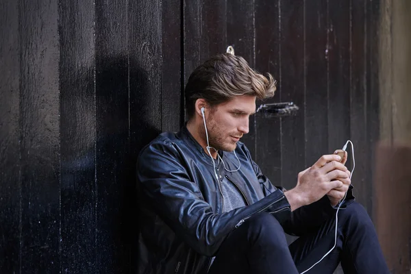 Hombre joven escuchando música teléfonos inteligentes auriculares —  Fotos de Stock