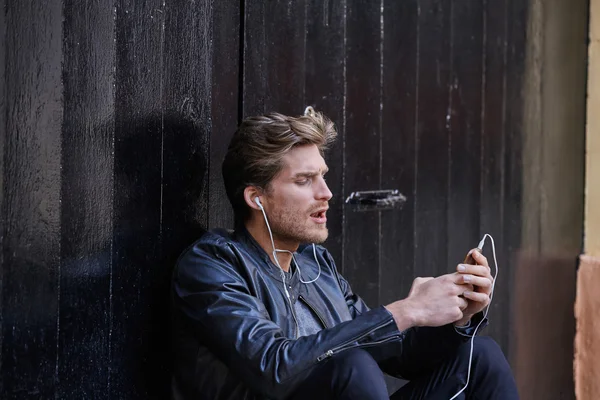 Молодой человек слушает музыку наушники смартфона — стоковое фото