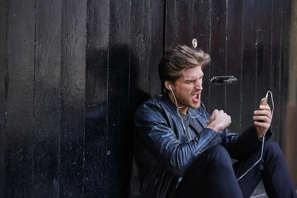 Hombre joven escuchando música teléfonos inteligentes auriculares —  Fotos de Stock