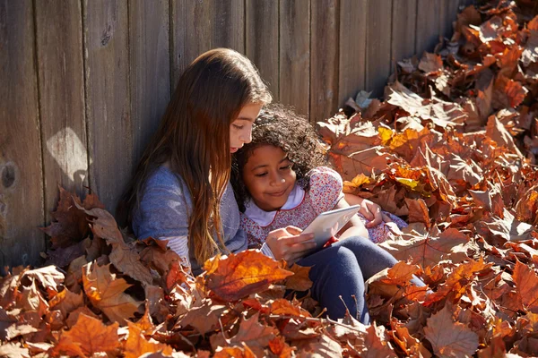 Παιδί κορίτσι φίλοι παίζουν pc ταμπλετών στα Φθινοπωρινά φύλλα — Φωτογραφία Αρχείου
