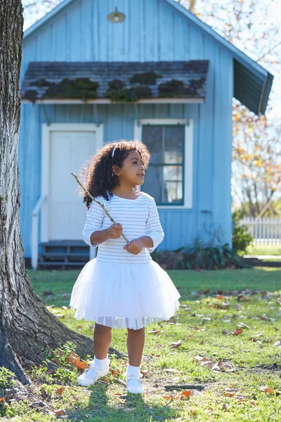 Дитяча дівчинка з гілкою палицею грає на відкритому повітрі — стокове фото