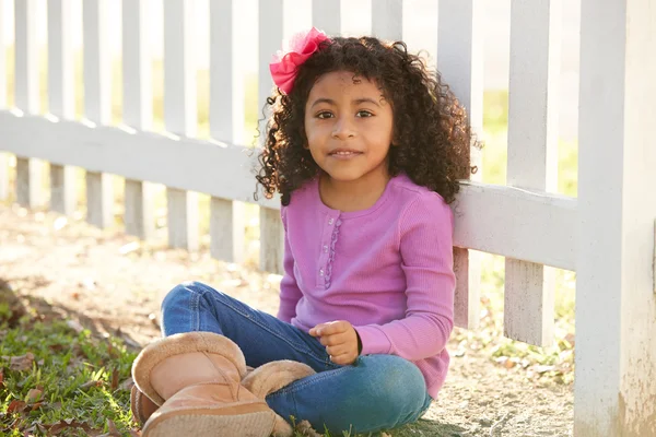Glada barnet kid flicka stående i en park staket — Stockfoto