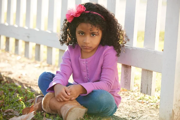 Triste niño niña retrato en un parque valla —  Fotos de Stock