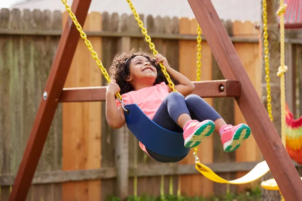 Niño niño niña balanceándose en un columpio de patio de recreo — Foto de Stock