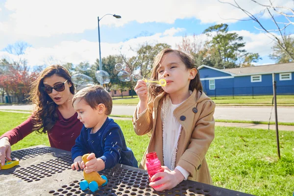 Mor dotter och son på park blåser bubblor — Stockfoto