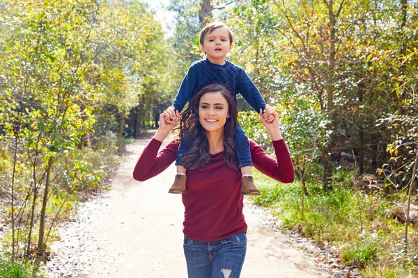 Niño niño sentarse en la madre hombros caminar parque — Foto de Stock