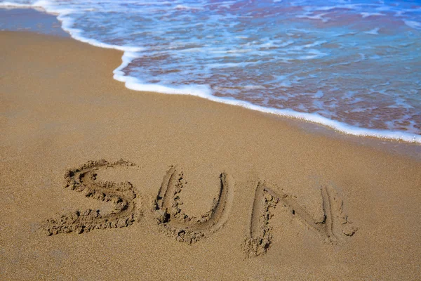 Sol soletrar trabalho escrito na areia de uma praia — Fotografia de Stock