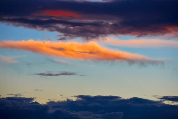 Nubes anaranjadas al atardecer en cielo azul — Foto de Stock