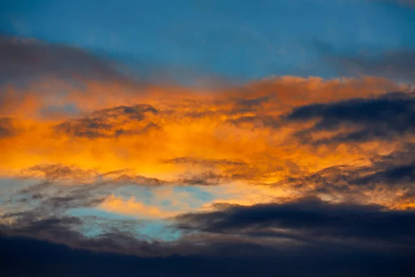 Nubes anaranjadas al atardecer en cielo azul — Foto de Stock