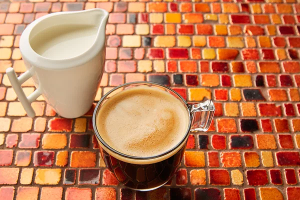 Copo de vidro de café com creme em telhas mesa vermelha — Fotografia de Stock