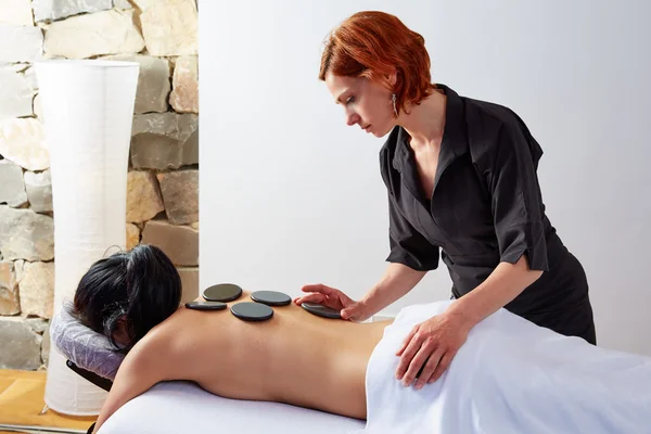 Massagem de pedra quente na mulher de volta fisioterapeuta — Fotografia de Stock