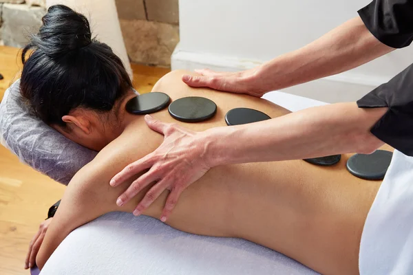 Massagem de pedra quente na mulher de volta fisioterapeuta — Fotografia de Stock