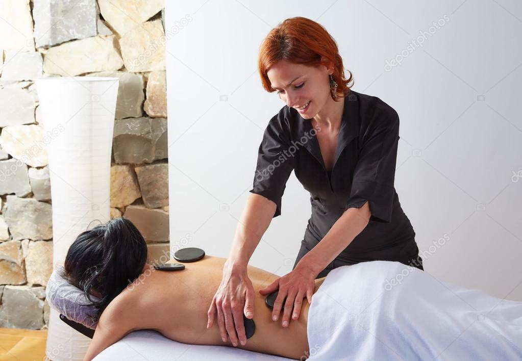 Hot stone massage in woman back physiotherapist