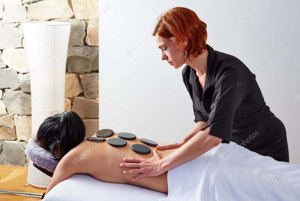 Hot stone massage in woman back physiotherapist