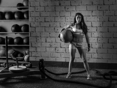 Ağırlıklı topu tutan esmer spor salonu kız