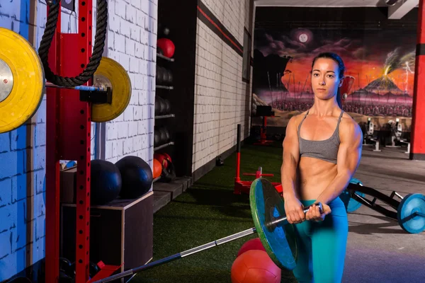 Chica del gimnasio levantando una barra con el cuerpo en forma — Foto de Stock