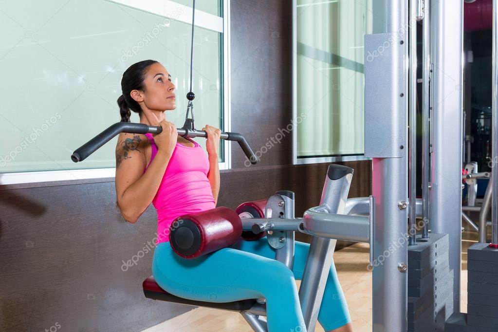 Professional woman athlete using the pulley machine Stock Photo by