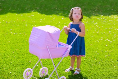 Yürümeye başlayan çocuk kız bebek arabası yeşil çim ile oynarken