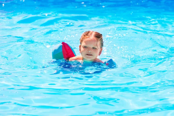 Niña nadando en la piscina con mangas flotantes — Foto de Stock