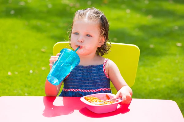Bambino bambino ragazza bere mangiare pasta in giardino — Foto Stock