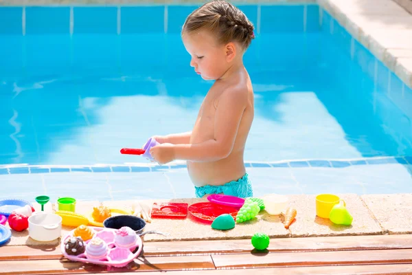 Toddler kid girl playing food toys in swimming pool — Stock Photo, Image