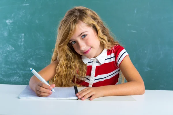 Estudante loira escrevendo caderno na mesa de aula — Fotografia de Stock