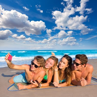 Selfie group of tourist friends in a tropical beach clipart