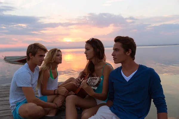 Grupo de amigos al atardecer playa divertirse con la guitarra —  Fotos de Stock