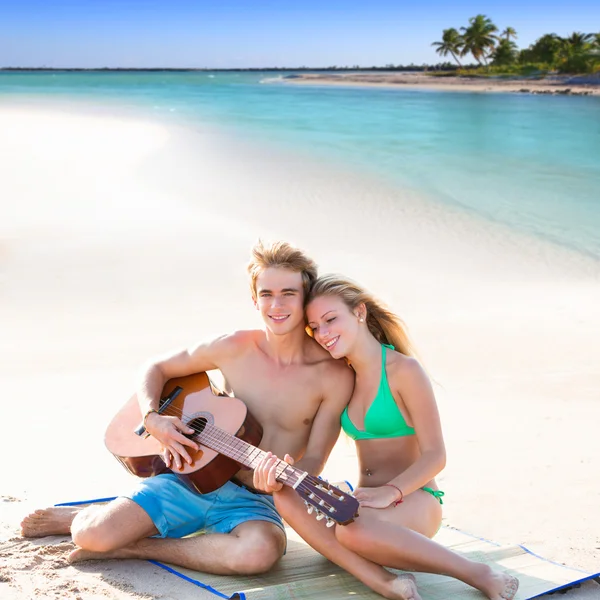 Blond tourist couple playing guitar at beach — Stock Photo, Image