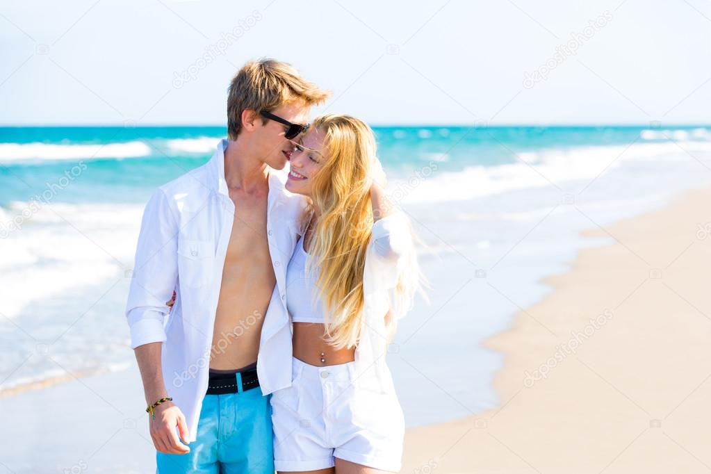 Blond teen couple walking together in the beach