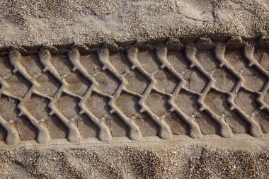 Araba tekerleği kumsalda ayak izi bırakıyor.