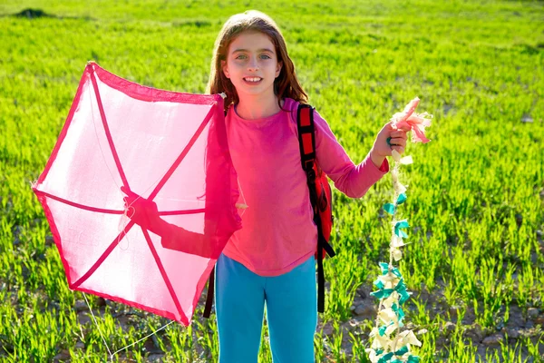 Pembe uçurtma bahar çayırda tutan çocuk kız — Stok fotoğraf