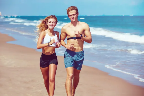 Loira jovem casal correndo em uma praia no verão — Fotografia de Stock