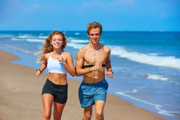 Pareja joven rubia corriendo en una playa en verano —  Fotos de Stock