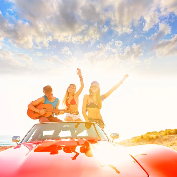 Young group having fun on beach playing guitar — Stock Photo, Image